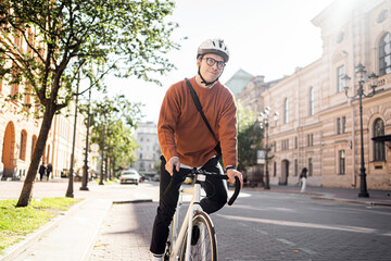 A man with glasses and a briefcase rides a bicycle on the road.