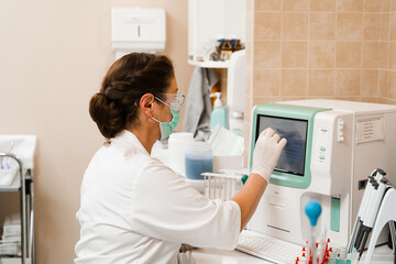 Laboratory assistant works on blood analyzer and makes hematological analysis in the laboratory. Medical equipment in the lab. Biochemical and hematological analysis of blood.