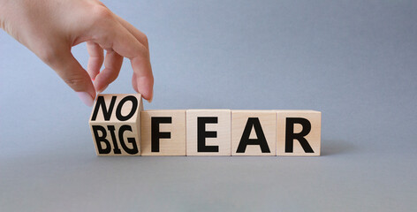 No fear vs big fear symbol. Businessman hand turnes wooden cubes and changes word Big fear to No Fear. Beautiful grey background. Business concept. Copy space.