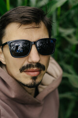 Large male portrait. A man in dark glasses with a mustache and beard.