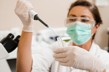 Laboratory assistant with dispenser in laboratory doing blood test analysis. Medical equipment in lab. Scientist with blood dispenser doing hematological analysis of blood.