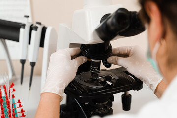 Laboratory assistant looks into microscope and makes blood test in the laboratory. Medical equipment for hematological and biochemical blood tests in a medical clinic.