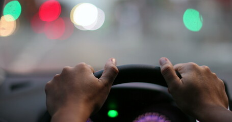 Driver POV hands holding steering wheel waiting. Person hand close-up point of view in red light