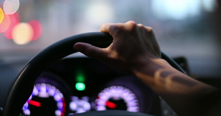 Closeup driver POV holding steering wheel driving at night - obrazy, fototapety, plakaty