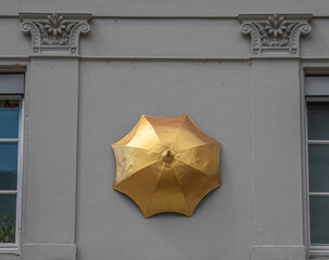 Zurich, Switzerland - Juli 10, 2022: Historical model of a golden umbrella on the wall of the former umbrella factory at Munsterhof in Zurich, Switzerland