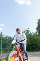 A smiling African-American man rides a bicycle through a public park. Portrait. Sports and recreation