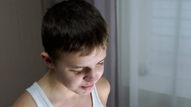 Face of a Guilty, Speaking Smiling Teenager with a Downcast Look. Side view. Conflict with parents, repentance, punishment, awareness of guilt. Behavior, emotion, reaction, dialogue. Childhood age.