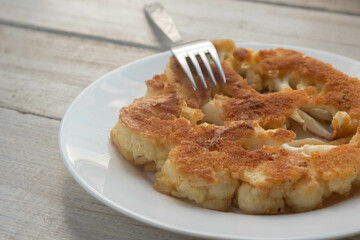 Close-up of fried cauliflower schnitzel on a plate on a wooden table. The concept of vegetarianism.