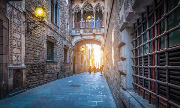 Narrow street with popular bridge in Gothic Quarter at dusk, Barcelona Spain.  