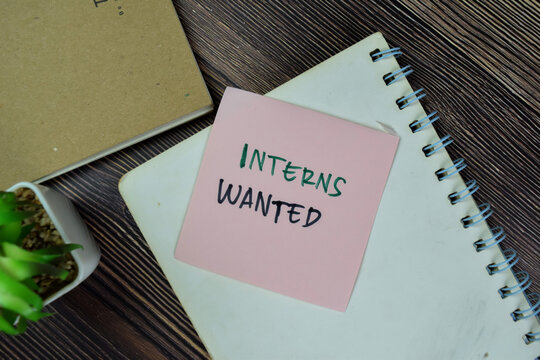 Concept of Interns Wanted write on sticky notes isolated on Wooden Table.
