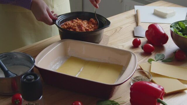 Woman is cooking tasty Italian meal, lasagna, mixing hot meat sauce, aromatic and tasty food prepared at home, Foreground, Slow motion.