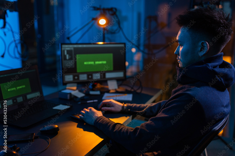 Poster cybercrime, hacking and technology concept - male hacker in dark room writing code or using computer