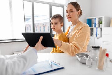 medicine, healthcare and pediatry concept - smiling mother with little son and doctor with tablet pc computer at clinic