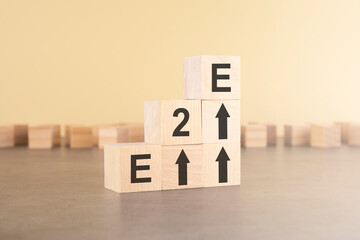 E2E - End to End - an abbreviation of wooden blocks with letters on a gray background.
