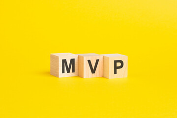 wooden blocks with text MVP on yellow background. business concept