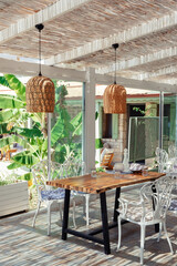 Summer cozy cafe with wicker lamps and solid wood furniture, mediterranean style. Light and shade.