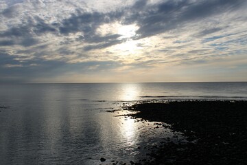 An atmospheric sky over the Irish sea with the sun reflecting off the water