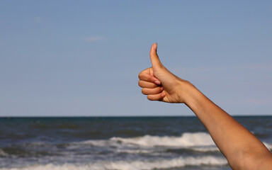 thumb up to indicate that all is well by the sea