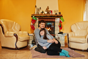 Happy young couple at home by a fireplace in warm living room on winter day.