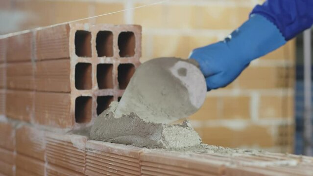 Pedreiro assentando tijolos com cimento em obra. Constru&ccedil;&atilde;o de casa ou pr&eacute;dio.