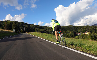 Obraz premium young cyclist with racing bicycle rides fast seen from behind