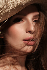 Portrait of a beautiful woman in a straw hat, loose hair and nude makeup. Beauty face