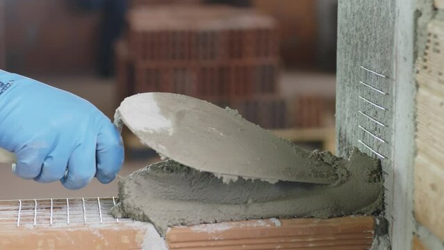 Pedreiro assentando tijolos com cimento em obra. Constru&ccedil;&atilde;o de casa ou pr&eacute;dio.