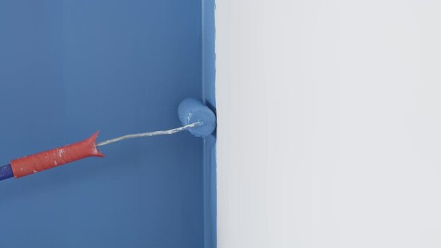 Parede branca sendo pintada de azul com rolo de pintura. 