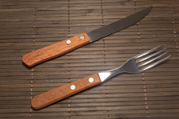 A fork and a knife on a surface made from thin strips of wood