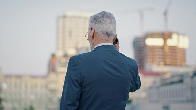 Elderly businessman calls to client standing on street