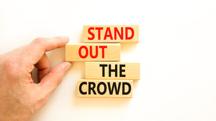 Stand out the crowd symbol. Concept words Stand out the crowd on wooden blocks on beautiful white table white background. Businessman hand. Business, stand out the crowd concept
