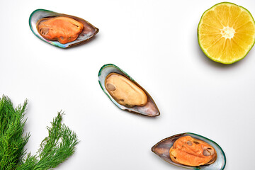 mussels opened with a slice of lemon and a sprig of dill on a white background top view