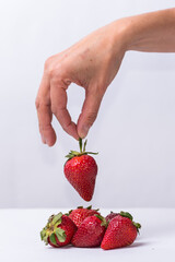 Obraz premium fingers choosing a red strawberry, fruit, healthy living, lifestyle