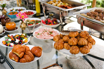 croissants, profiteroles, sweet sauces on the buffet table