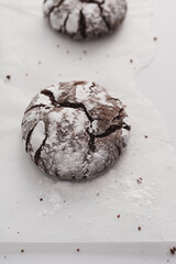 Food photo of freshly baked Chocolate Crinkle Cookies. Top down view of chocolate iced biscuits on top of baking paper. Copy space available