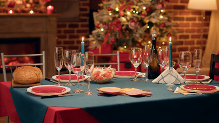 Empty interior of festive traditional Christmas dinner table with authentic decorative cutlery and dinnerware. Cozy and ornate looking living room with seasonal and positive style with nobody in it.