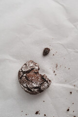 Top down view of a single Crinkle Cookie. Flay lay image of chocolate iced biscuit on top of baking paper. Copy space available
