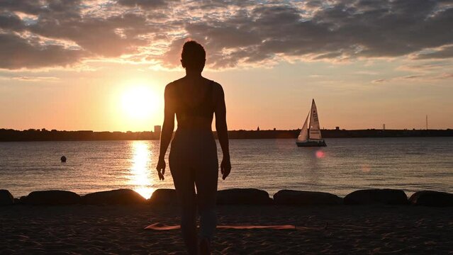 Slow motion video of a young woman doing yoga workout on Baltic sea coastline during subset