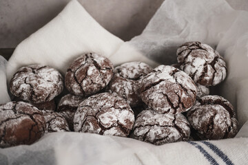 Food photo of freshly baked Chocolate Crinkle Cookies. Close up image of chocolate biscuits arranged in tin with baking paper.