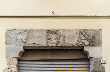 Architrave with bas reliefs of coat of arms, former hospital of San Pier Novello, built in 14th century, in via Romana (Roman street), Florence city center, Tuscany region, Italy - obrazy, fototapety, plakaty