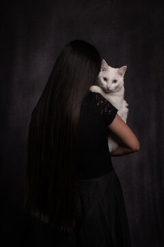 classic studio portrait of woman in black with a sweet white cat on shoulder 
