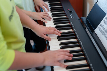 Fototapeta premium Midi keyboard or electronic piano and children's hands playing. Music education for a child in a music school. Individual music lessons with a teacher for school children. Selective focus