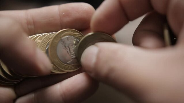 shallow focus shot from a man counting Brazilian Real coins in his hands