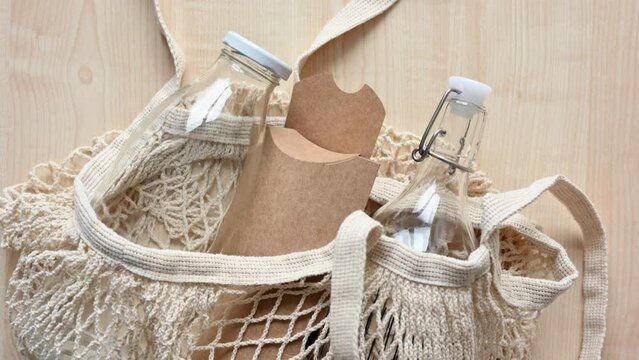 Reusable fabric shopping bag with glass bottles and paper eco-friendly packaging on the table. The concept of zero waste and the rejection of plastic in everyday life.