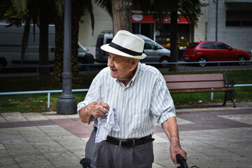 Abuelo anciano paseando con la ayuda de su andador con un sombrero 