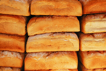 Freshly baked loaves of bread lie in rows. Baked goods stacked.