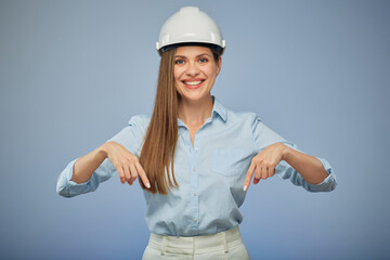 Woman in safety helmet pointing with finger down. Isolated female portrait.