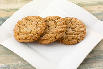 Three baked chewy ginger cookies on white snack plate