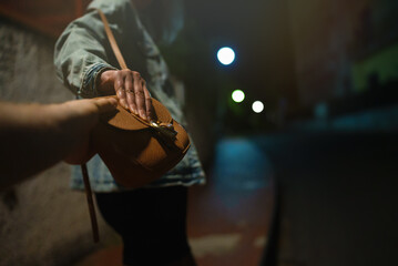 Thief snatches bag from woman on the night street. - obrazy, fototapety, plakaty
