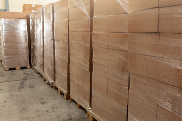 Warehouse of finished products. Cardboard boxes covered with plastic wrap on wooden pallets in warehouse